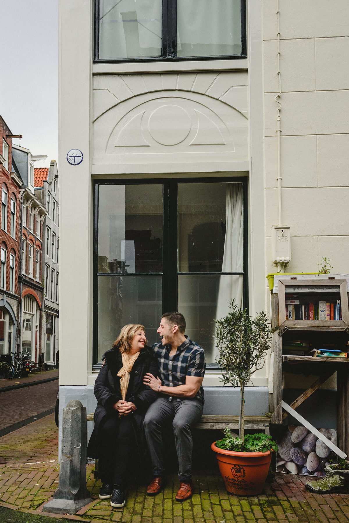 Mother and adult son leaning close together on a bench in Amsterdam, photographed during a birthday family session.