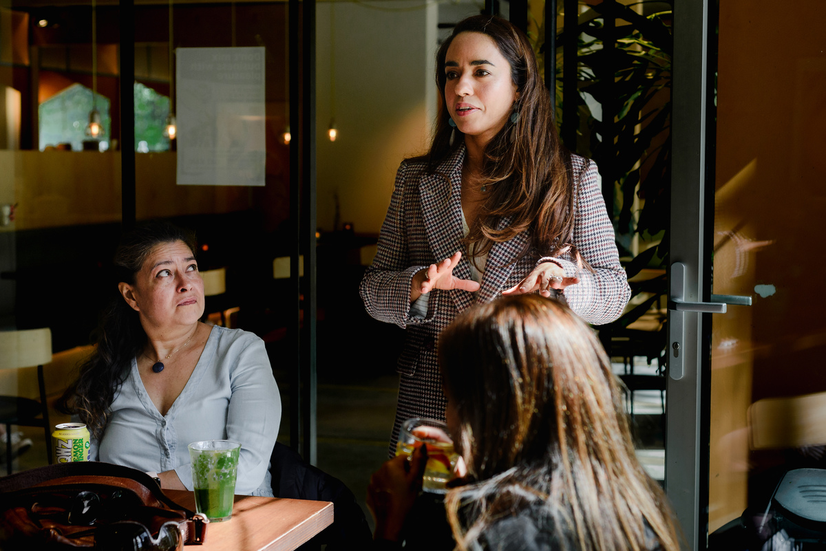 Small group of women seated at a table during a brunch event, listening and engaging in conversation.