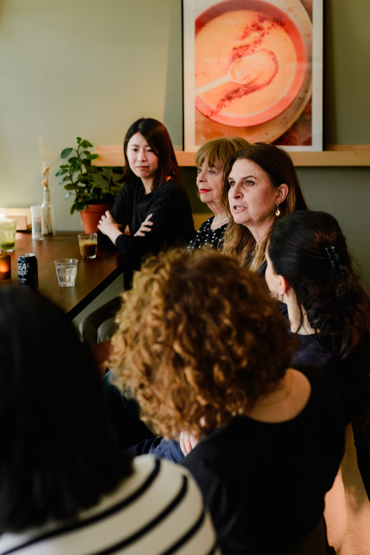 Group of women gathered around a table during an intimate brunch, engaged in conversation and connection.