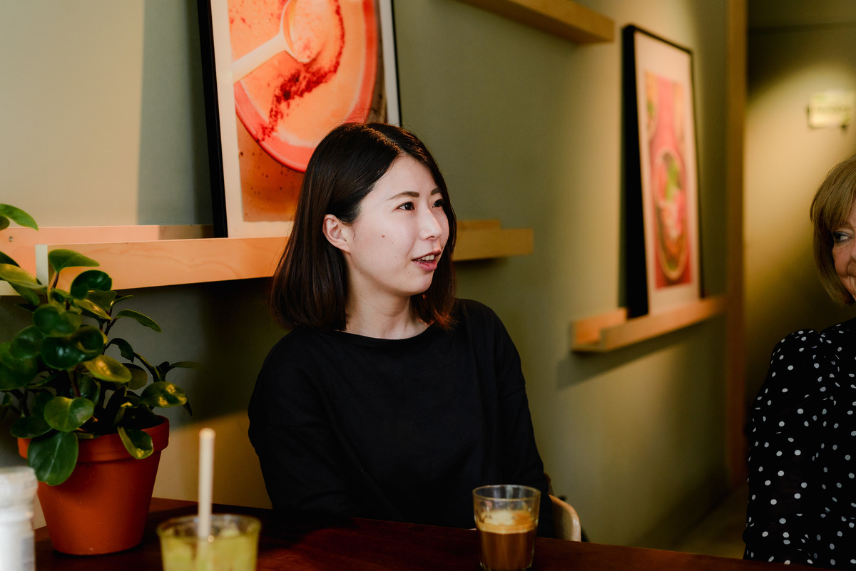 Portrait of a woman seated at a brunch table during a small Amsterdam event, with warm indoor light and relaxed atmosphere.