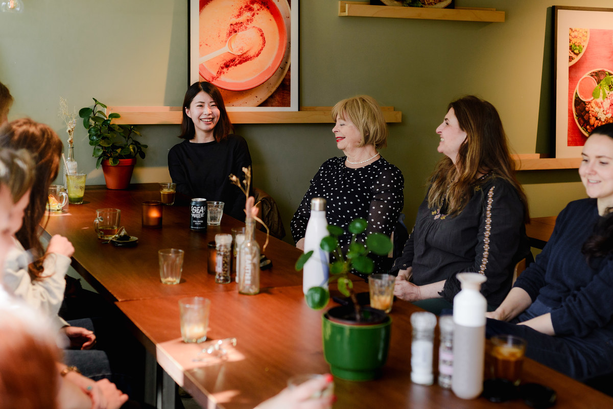 Group conversation during a community brunch in Amsterdam, showing multiple women connecting in a small, welcoming event.