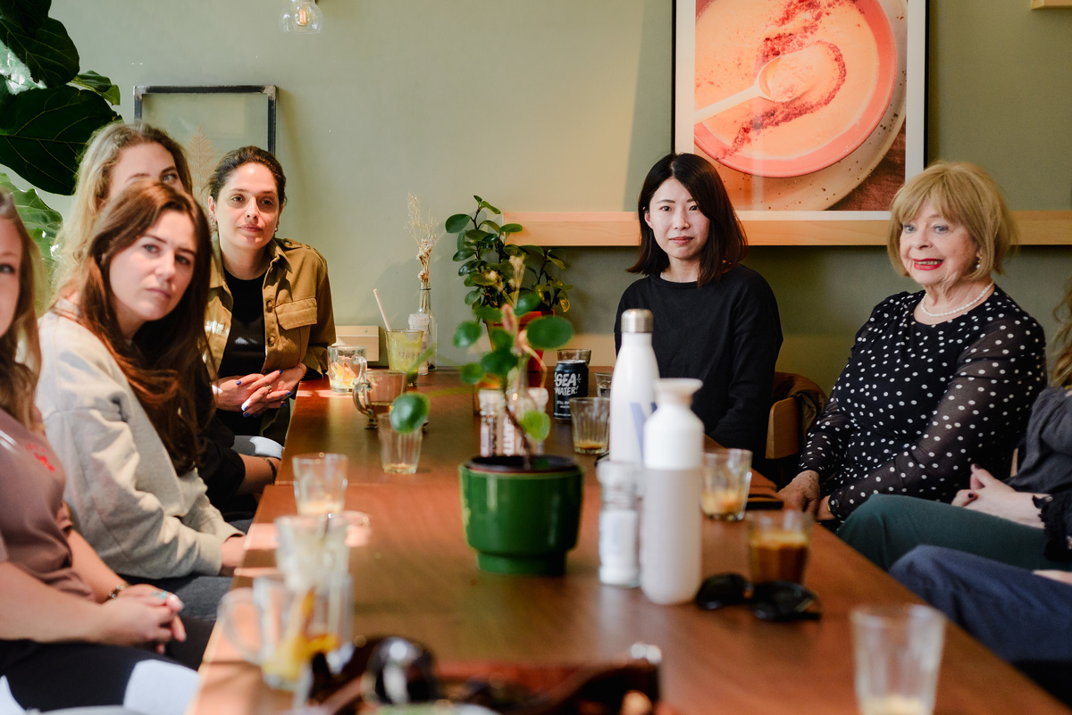 Wide view of an intimate brunch event in Amsterdam with women gathered around a table, highlighting connection, community, and shared moments.