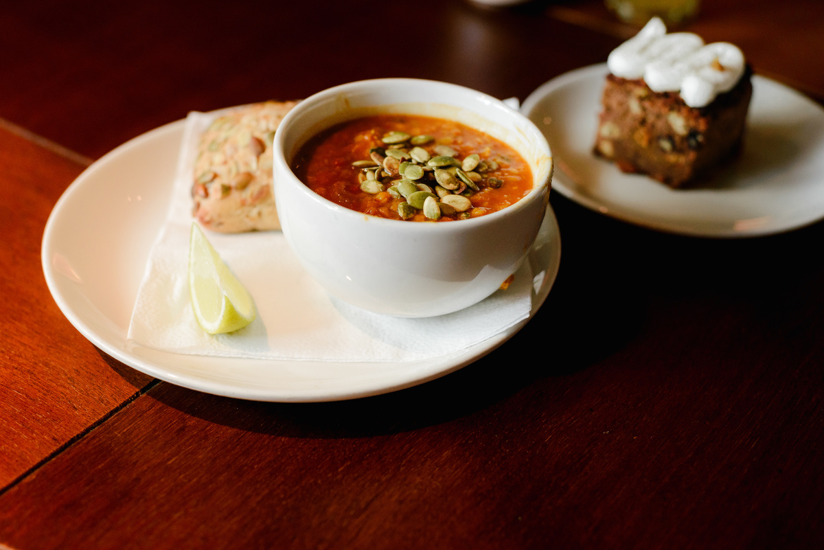 Close-up of brunch dish served at an Amsterdam community event, soup with seeds and bread on a wooden table.