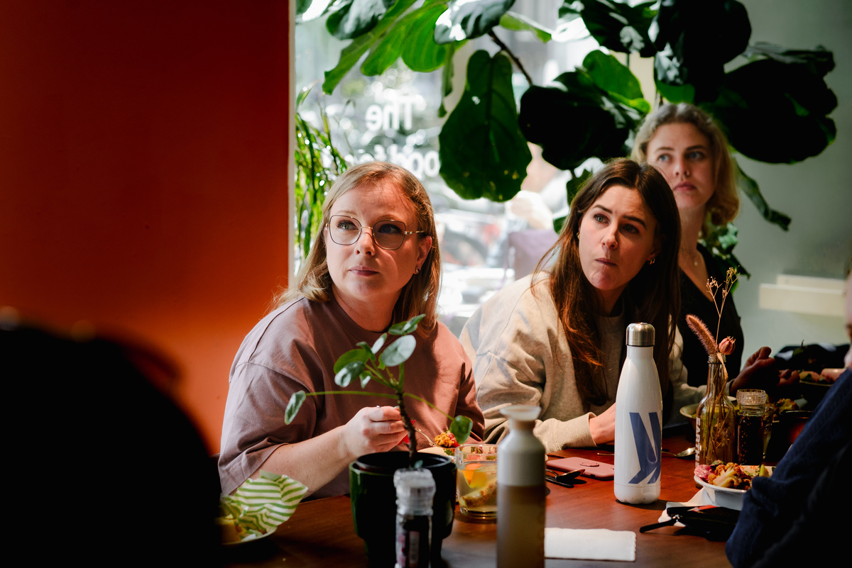 Women seated at a shared table during a community lunch, documented by an Amsterdam event photographer.