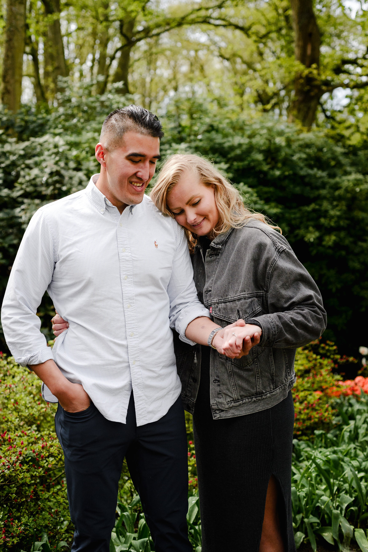 Bride showing her engagement ring while walking with her partner through Keukenhof tulip gardens.