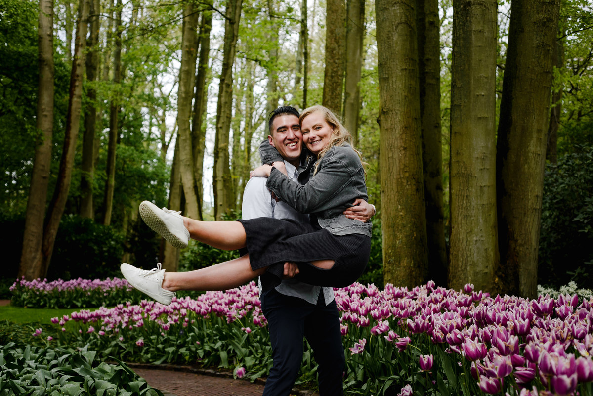 Couple celebrating engagement among purple tulips at Keukenhof Gardens in spring