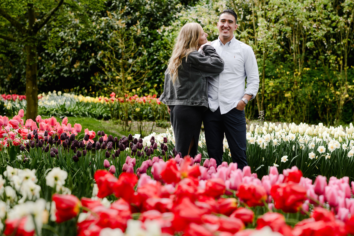 Couple sharing an intimate moment surrounded by red and white tulips