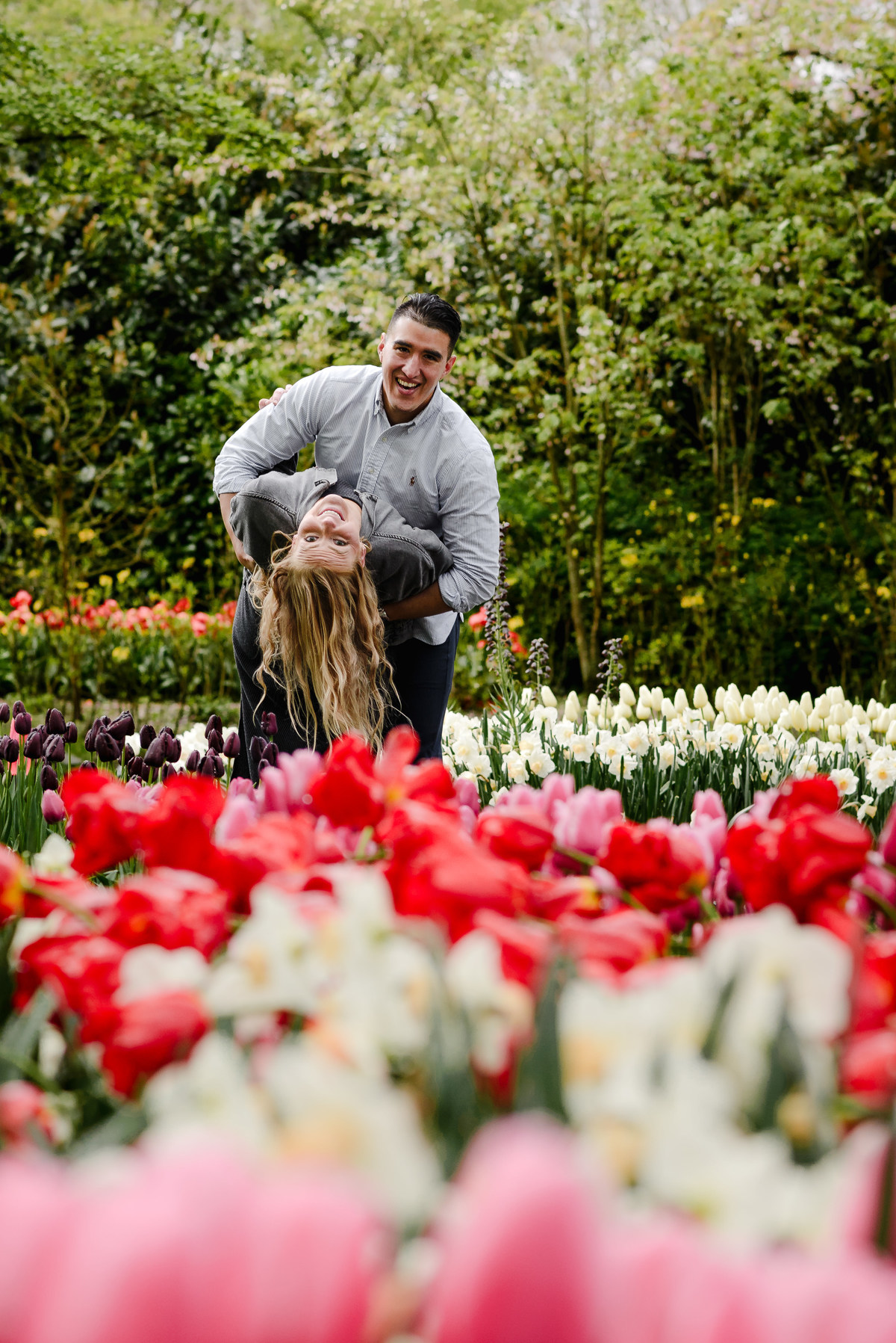 Couple sharing an intimate moment surrounded by red and white tulips
