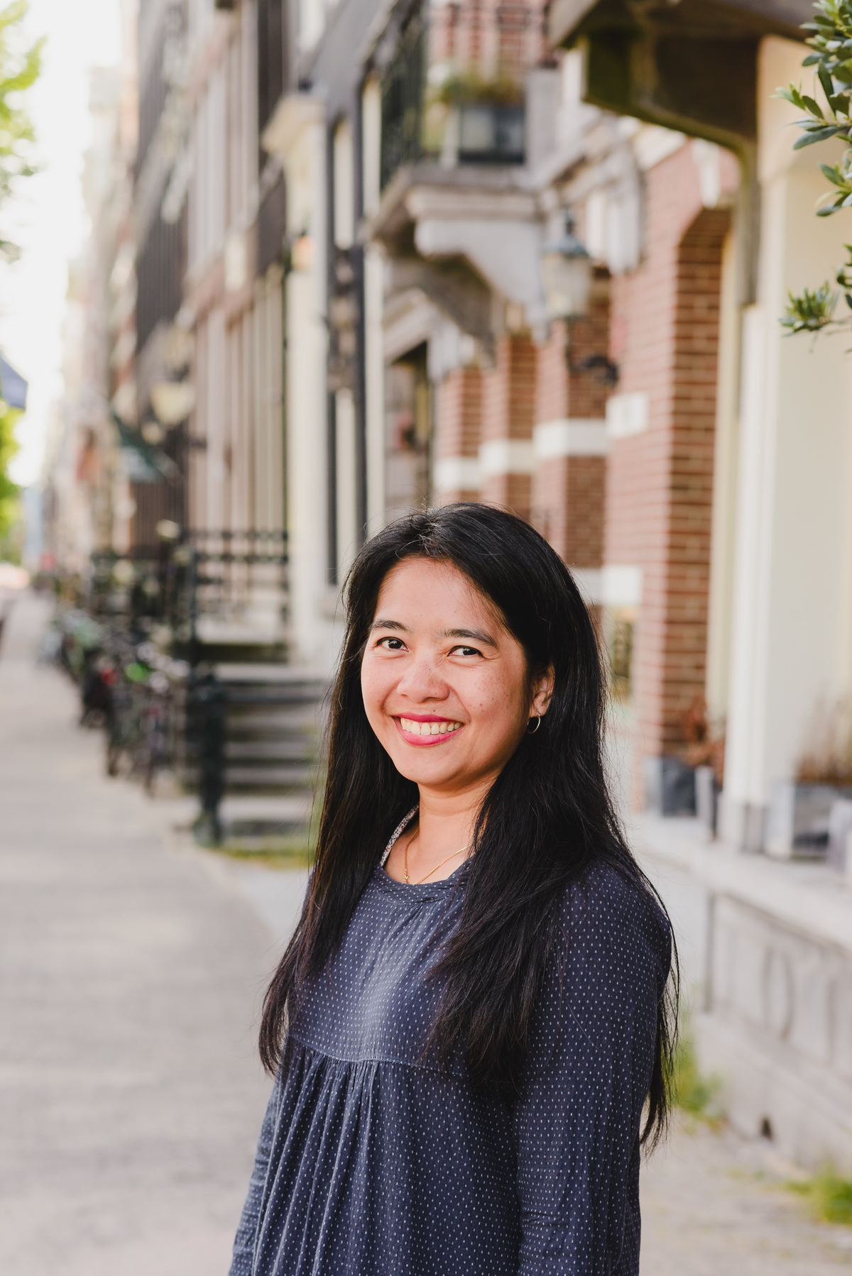 Close-up portrait of a woman smiling naturally on a quiet residential street in Amsterdam