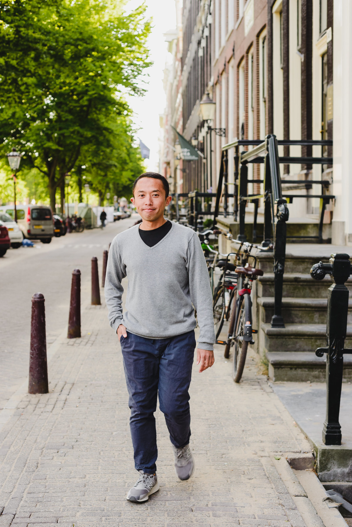 Man walking along a calm Amsterdam street lined with bicycles and historic buildings