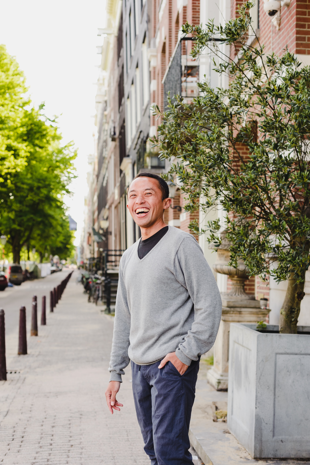 Man laughing during a casual photo session on a peaceful Amsterdam street