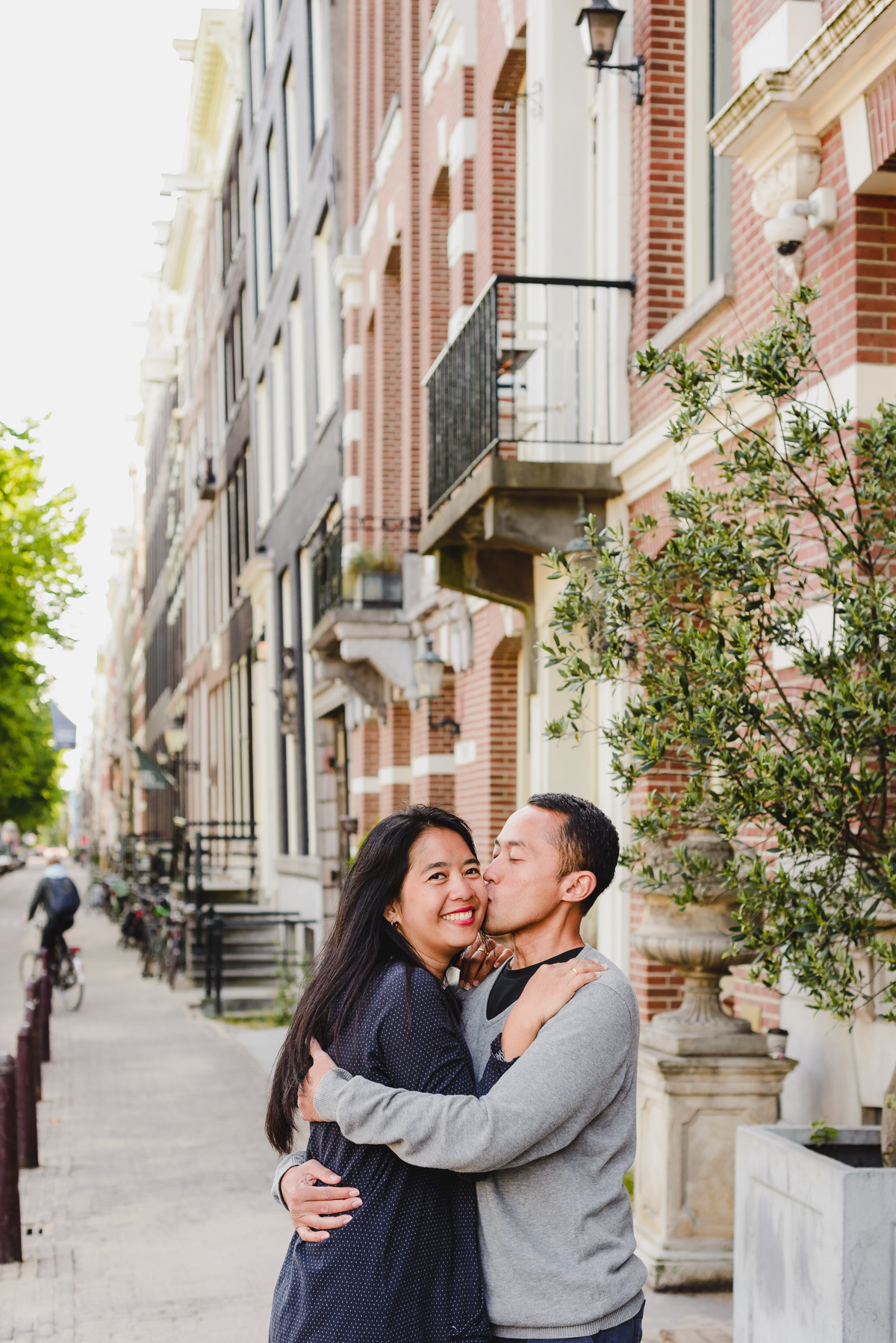 Couple smiling and embracing on a peaceful Amsterdam street during a natural and candid holiday photo shoot.
