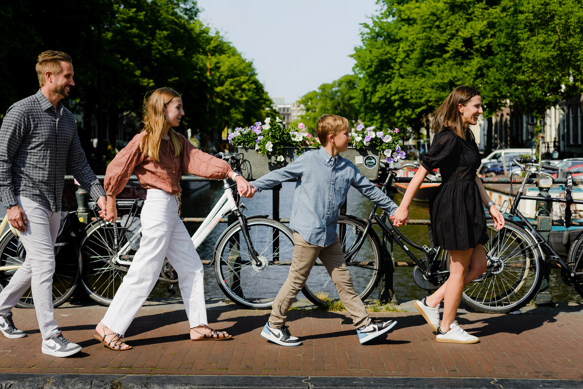 family walking together on an Amsterdam canal bridge with bicycles and historic buildings