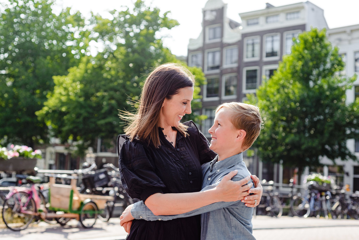 mother and son posing together on an Amsterdam canal bridge with bicycles and historic buildings