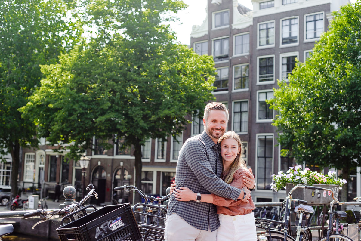 father and daughter posing together on an Amsterdam canal bridge with bicycles and historic buildings