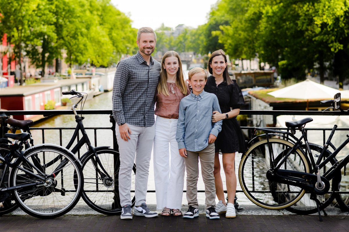 family posing together on an Amsterdam canal bridge with bicycles and historic buildings