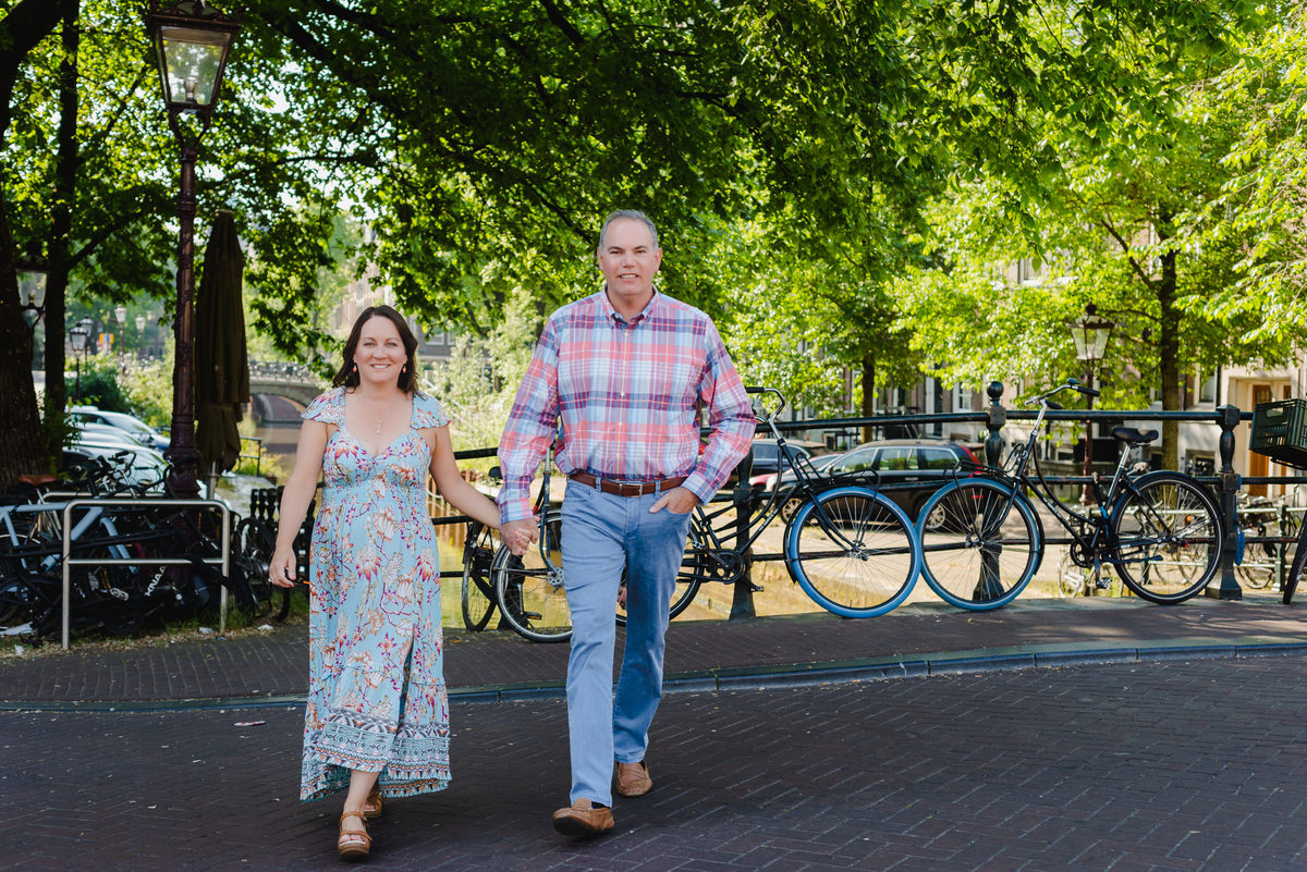 Couple walking along Amsterdam canal during anniversary trip