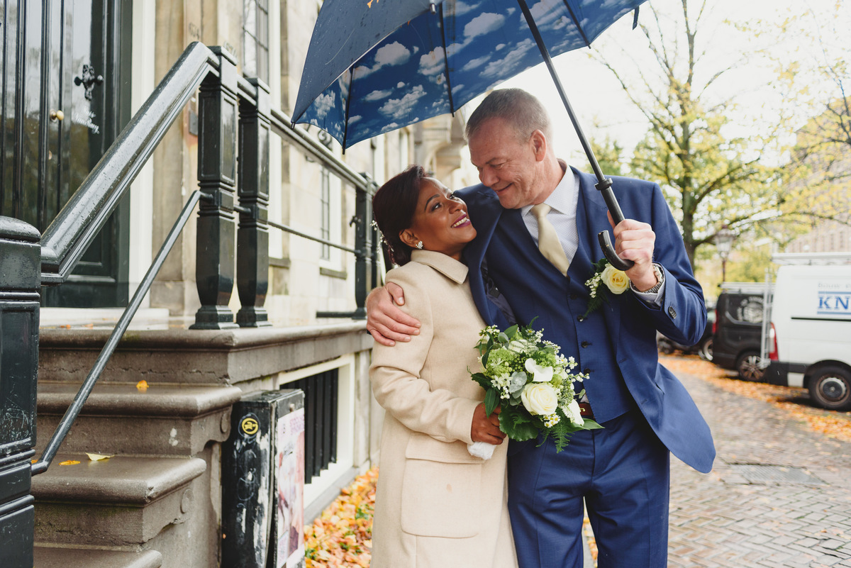 Bride and groom walking along Amsterdam canals toward Gemeente Amsterdam on the Amstel