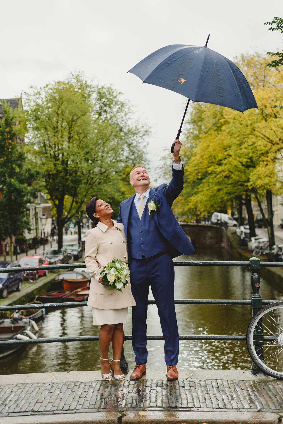 Couple walking under umbrella in light rain before civil wedding ceremony in Amsterdam