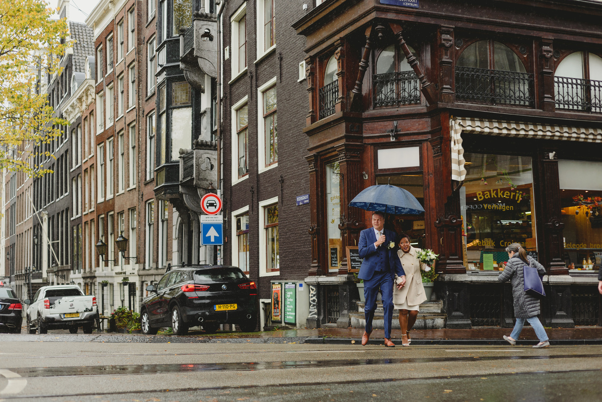 Bride and groom walking along Amsterdam canals toward Gemeente Amsterdam on the Amstel