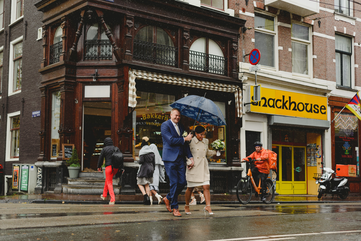 Bride and groom walking along Amsterdam canals toward Gemeente Amsterdam on the Amstel