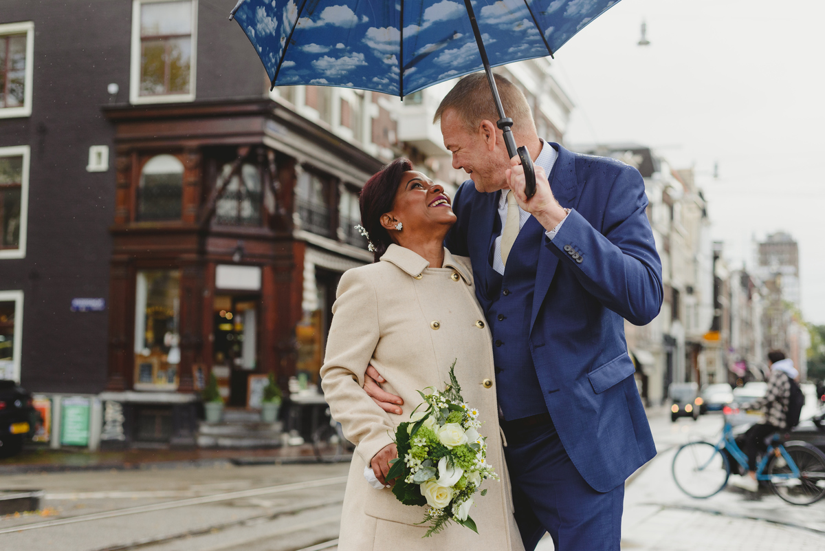 Bride and groom walking along Amsterdam canals toward Gemeente Amsterdam on the Amstel