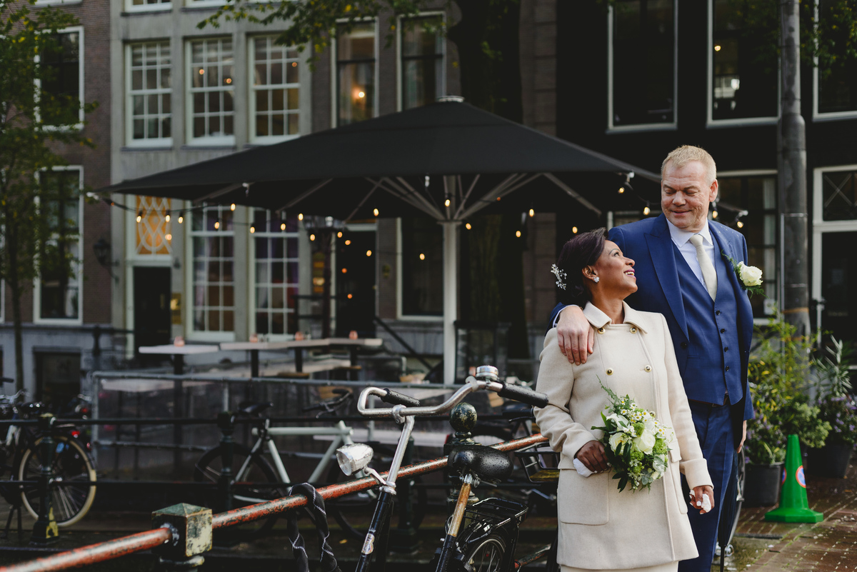 Couple walking under umbrella in light rain before civil wedding ceremony in Amsterdam