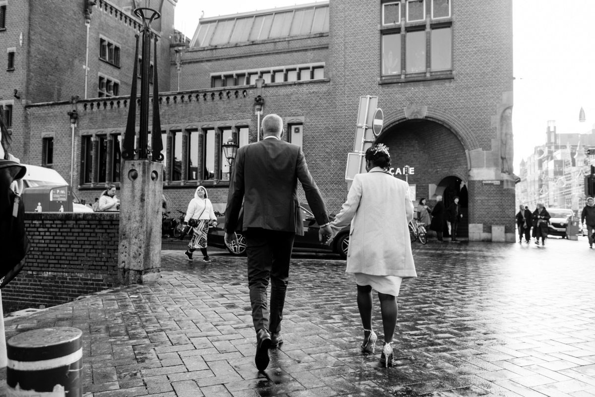 Bride and groom walking through Damrak after civil wedding in Amsterdam