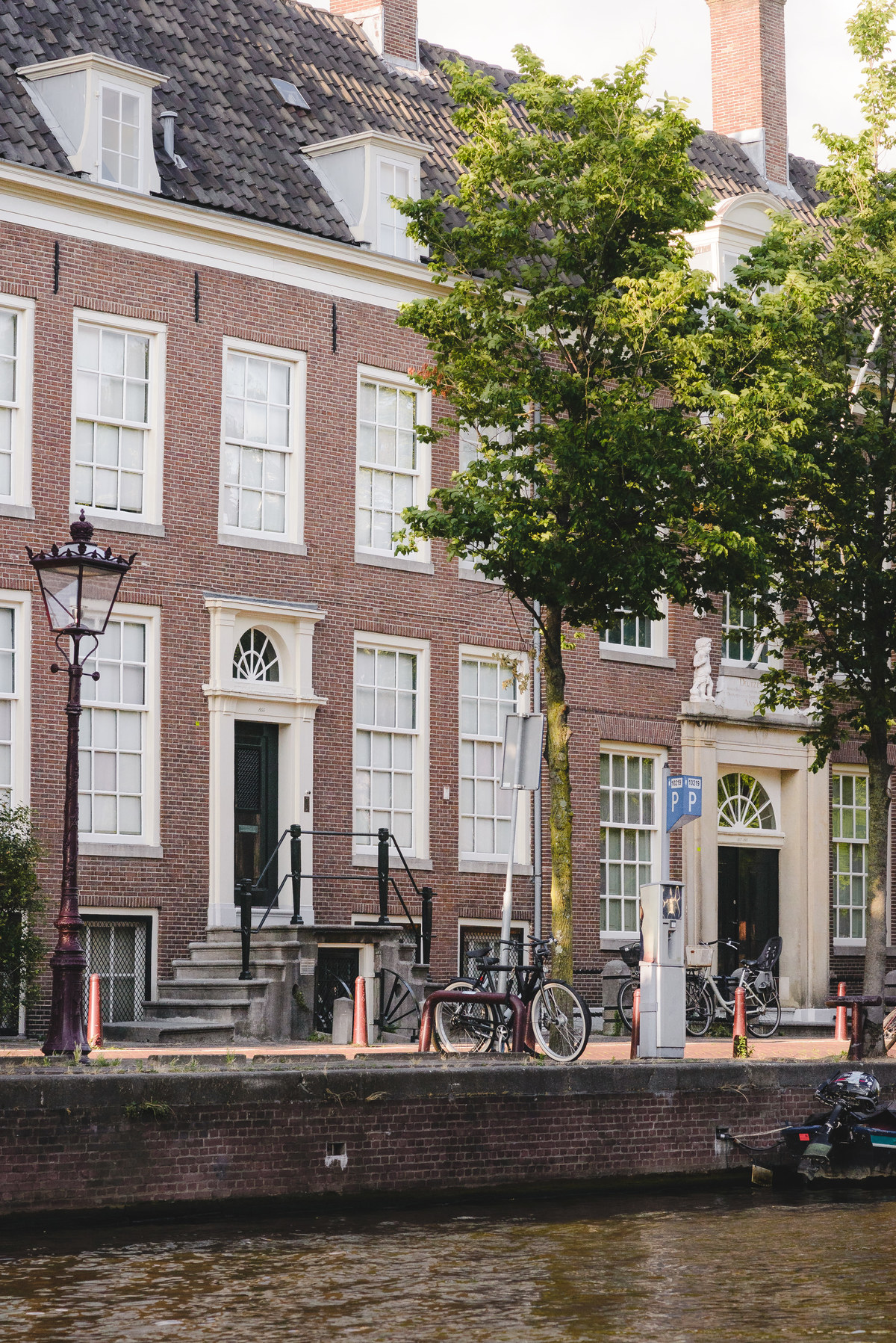 Historic canal houses in Amsterdam photographed from a boat during summer.