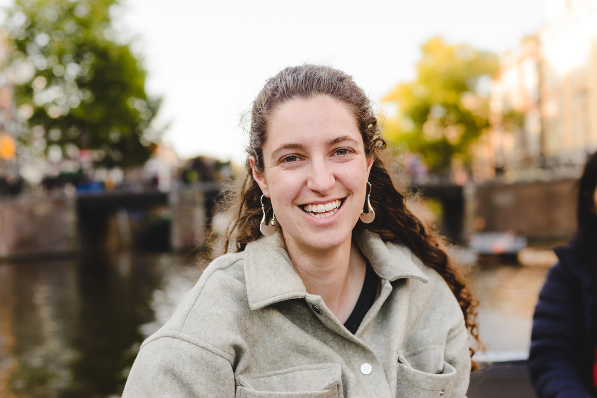 Person smiling while on an electric boat through Amsterdam canals on a sunny summer day.