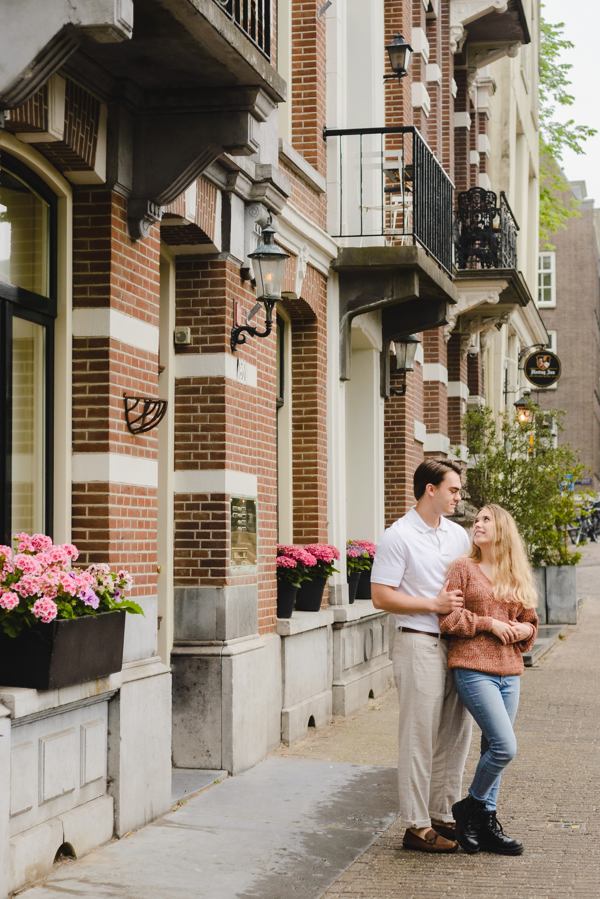 Couple laughing and spinning hands during a candid moment in Amsterdam city center