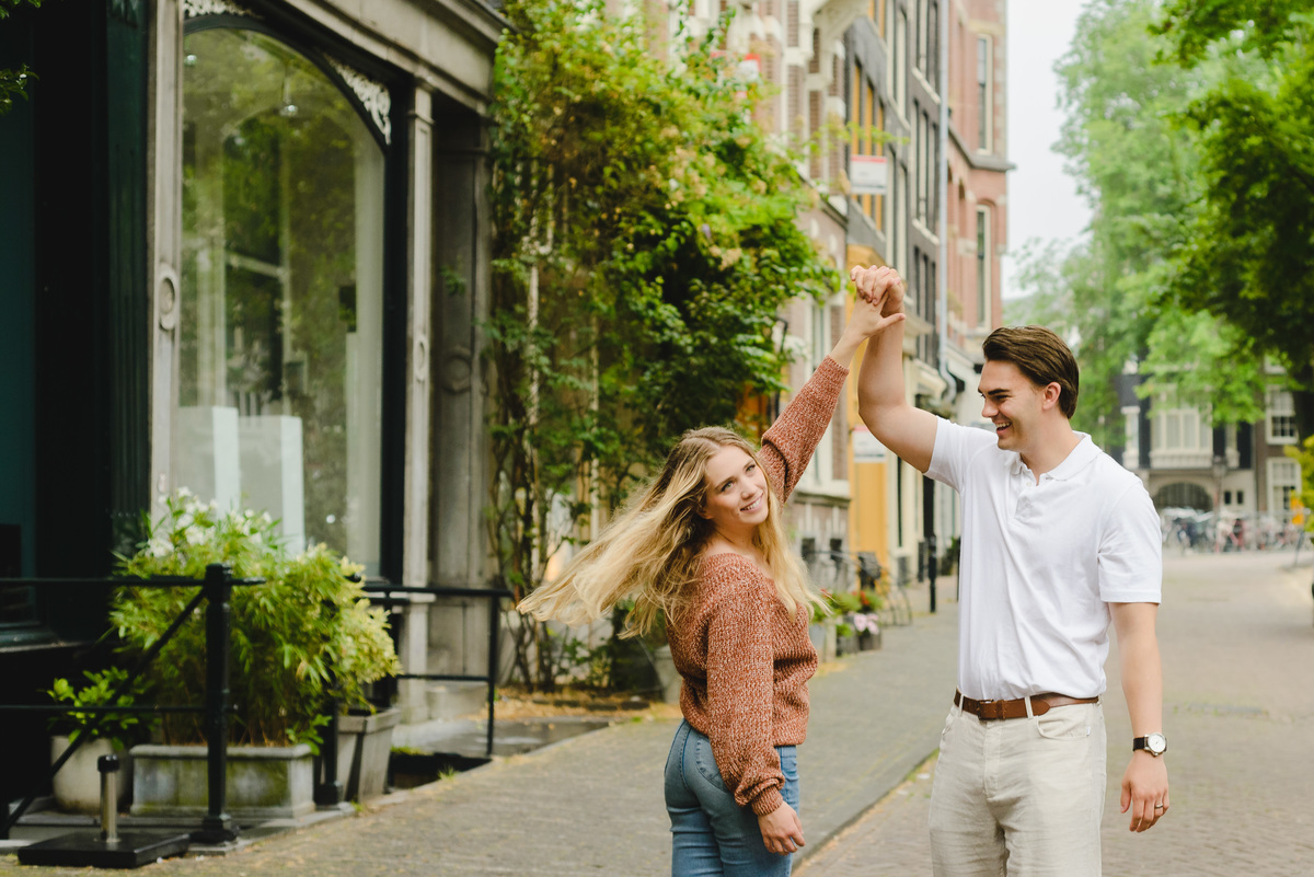 Couple laughing and spinning hands during a candid moment in Amsterdam city center