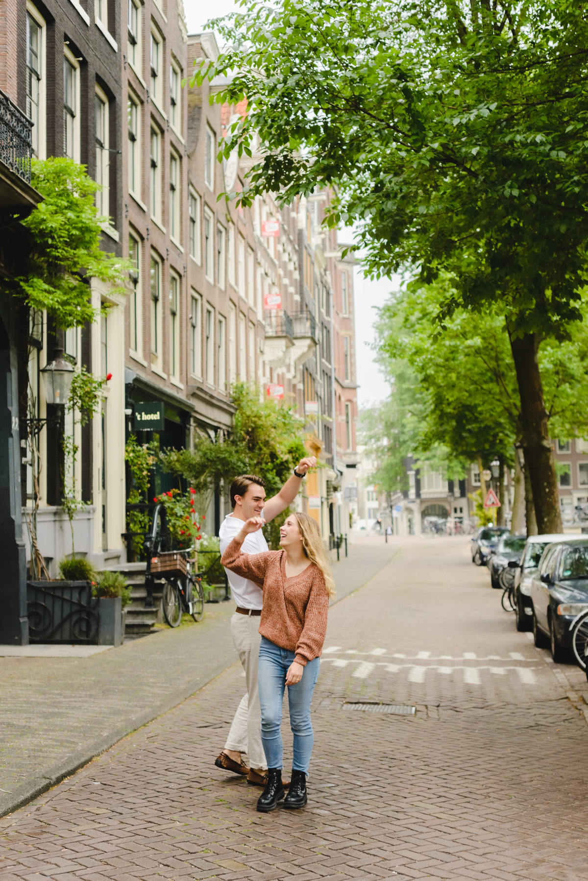 Couple laughing and spinning hands during a candid moment in Amsterdam city center