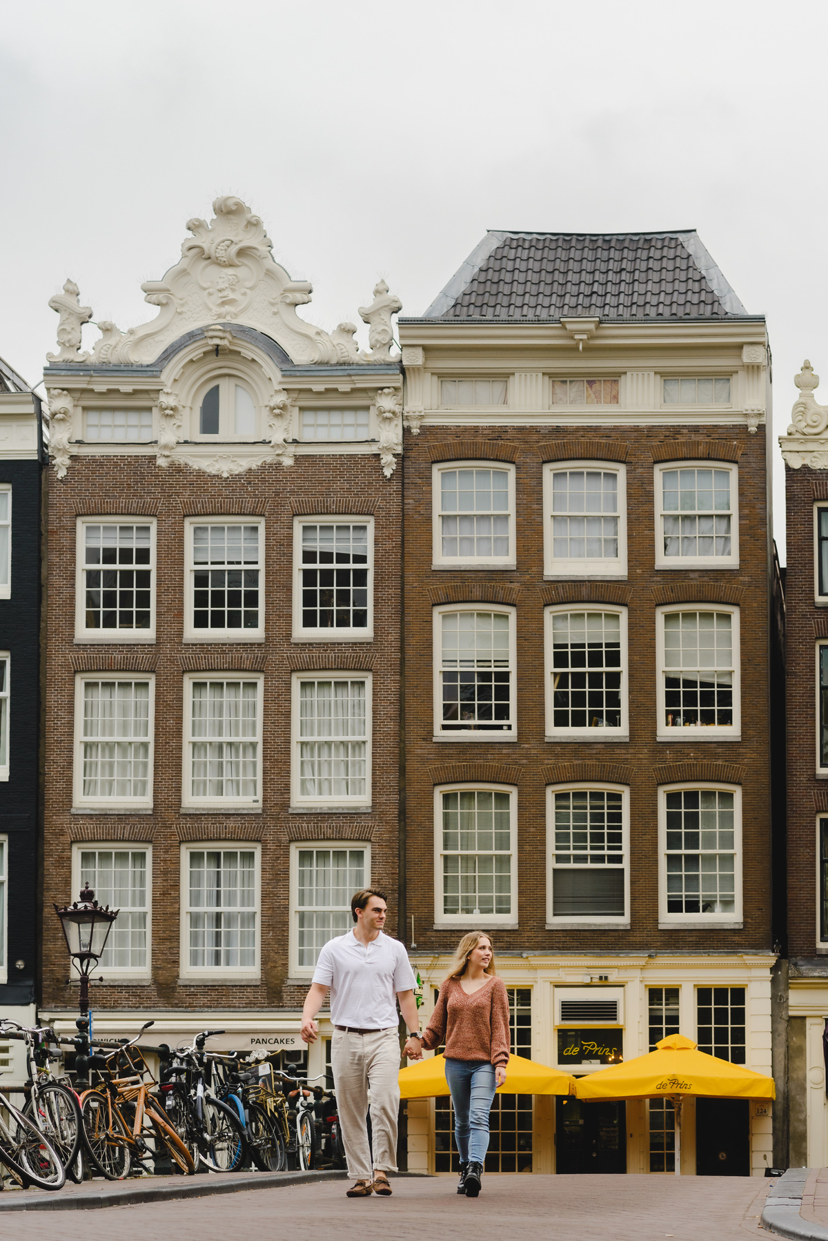 Documentary style couple photo capturing a relaxed walk near Amsterdam canals.