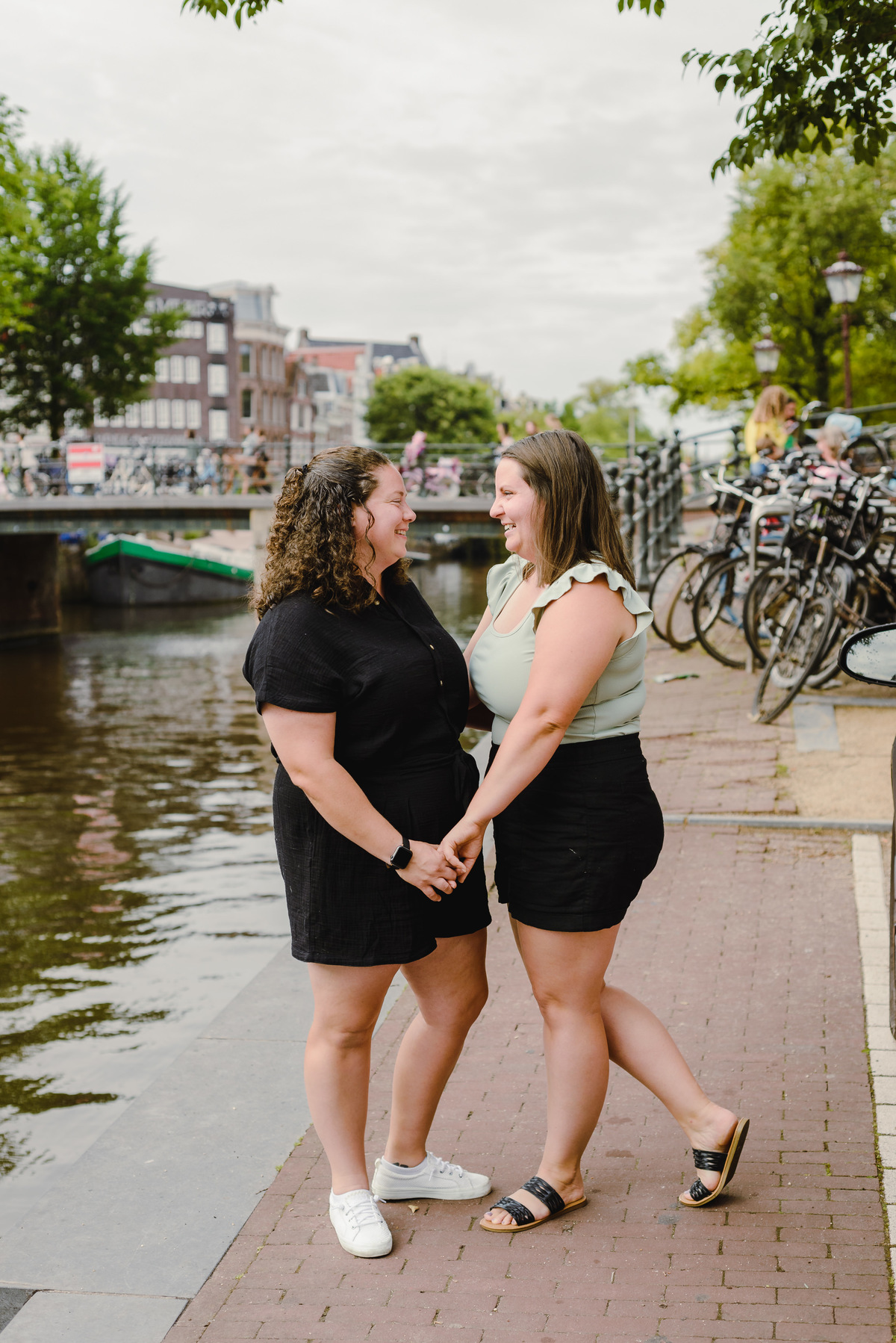Same-sex couple posing together in Amsterdam with canals and historic buildings