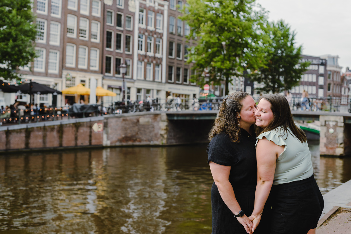 Same-sex couple photographed with historic Amsterdam architecture in the background