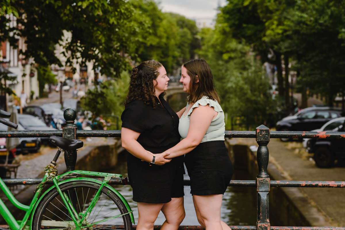 Same-sex couple posing together in Amsterdam with canals and historic buildings