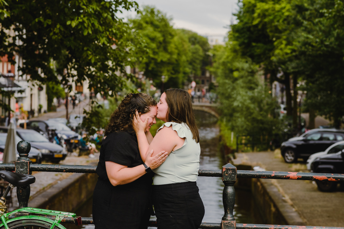 Same-sex couple posing together in Amsterdam with canals and historic buildings