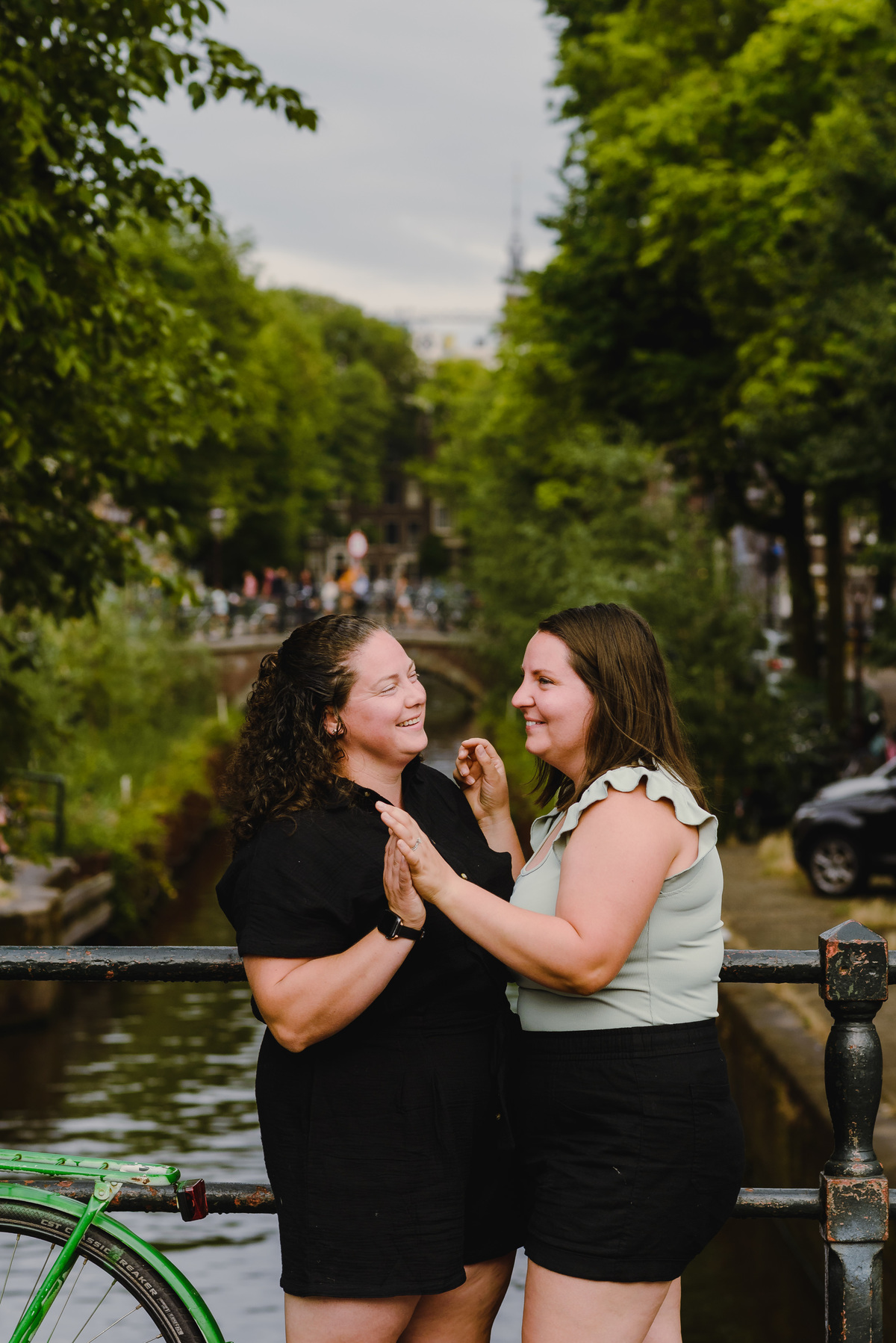 Same-sex couple posing together in Amsterdam with canals and historic buildings