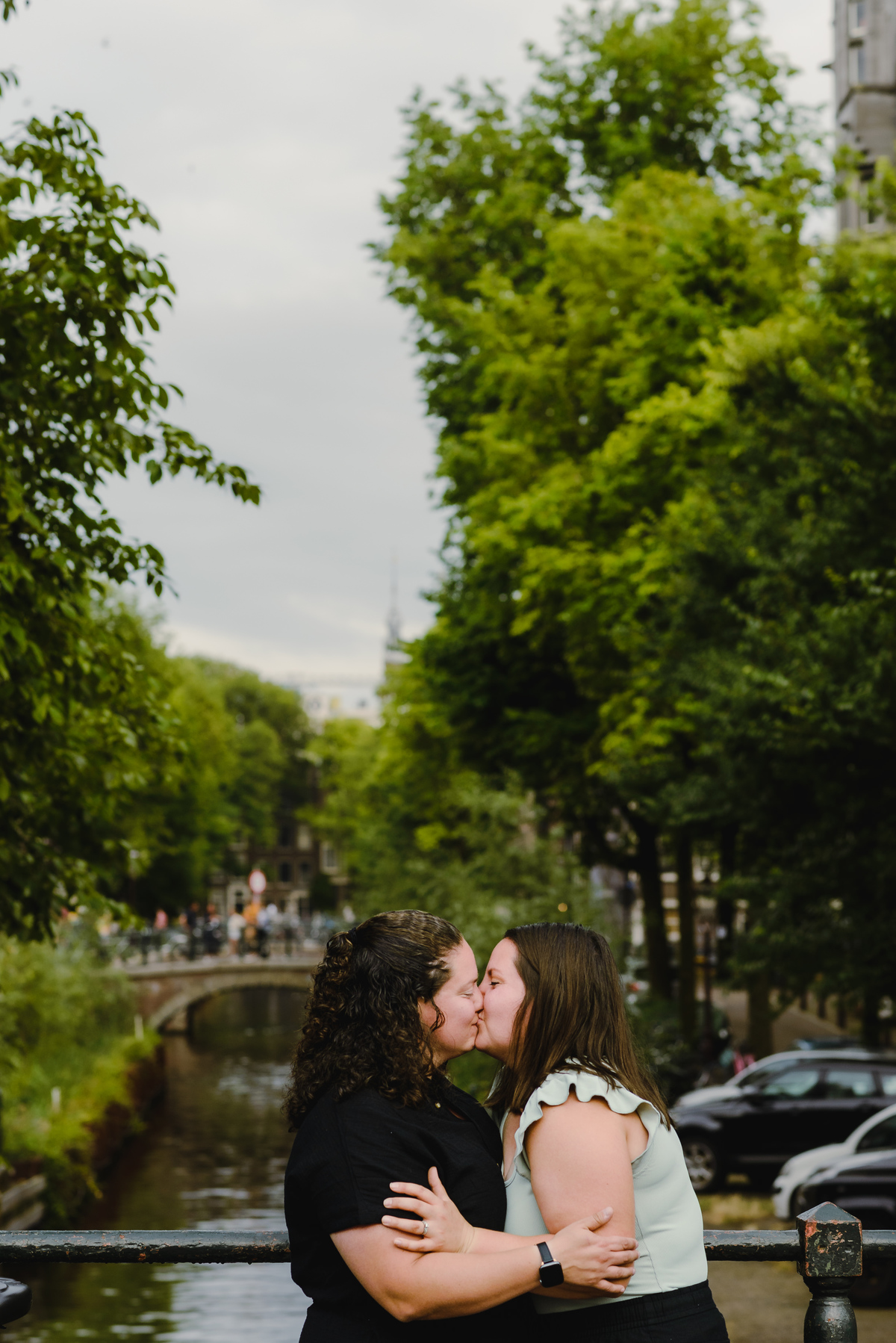 Same-sex couple posing together in Amsterdam with canals and historic buildings