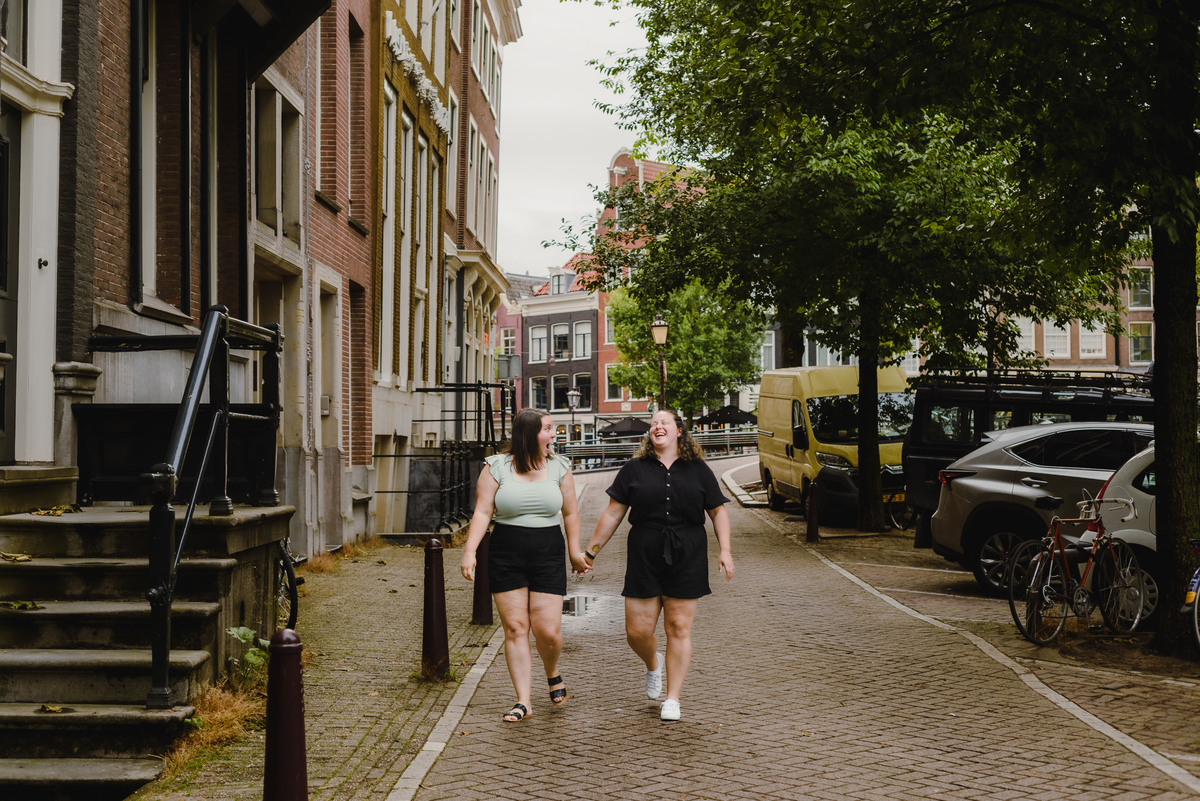 Romantic same-sex couple walking along an Amsterdam canal during a summer photo session