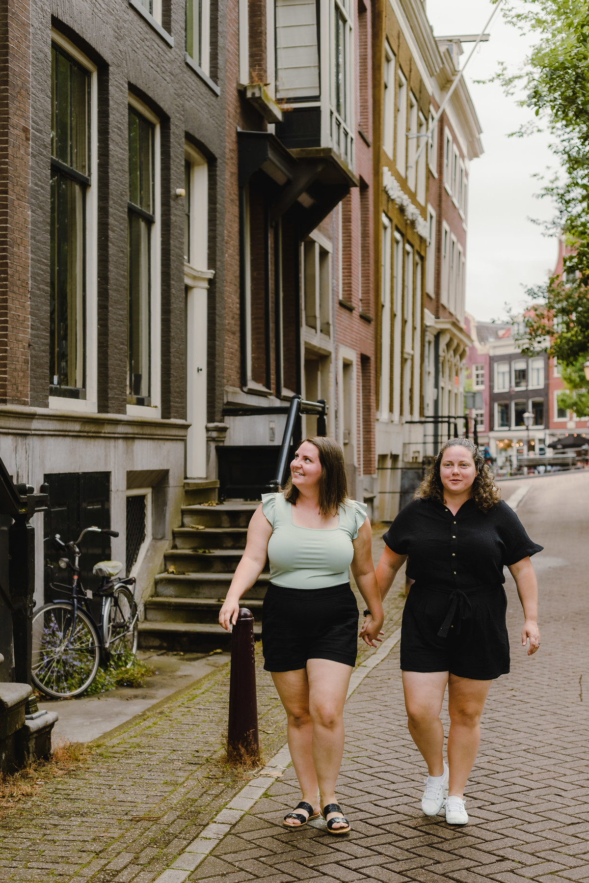 Romantic same-sex couple walking along an Amsterdam canal during a summer photo session