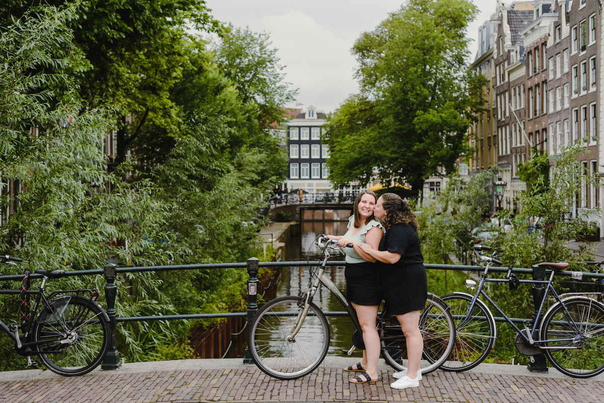Same-sex couple posing with a bicycle beside an Amsterdam canal, summer photo session