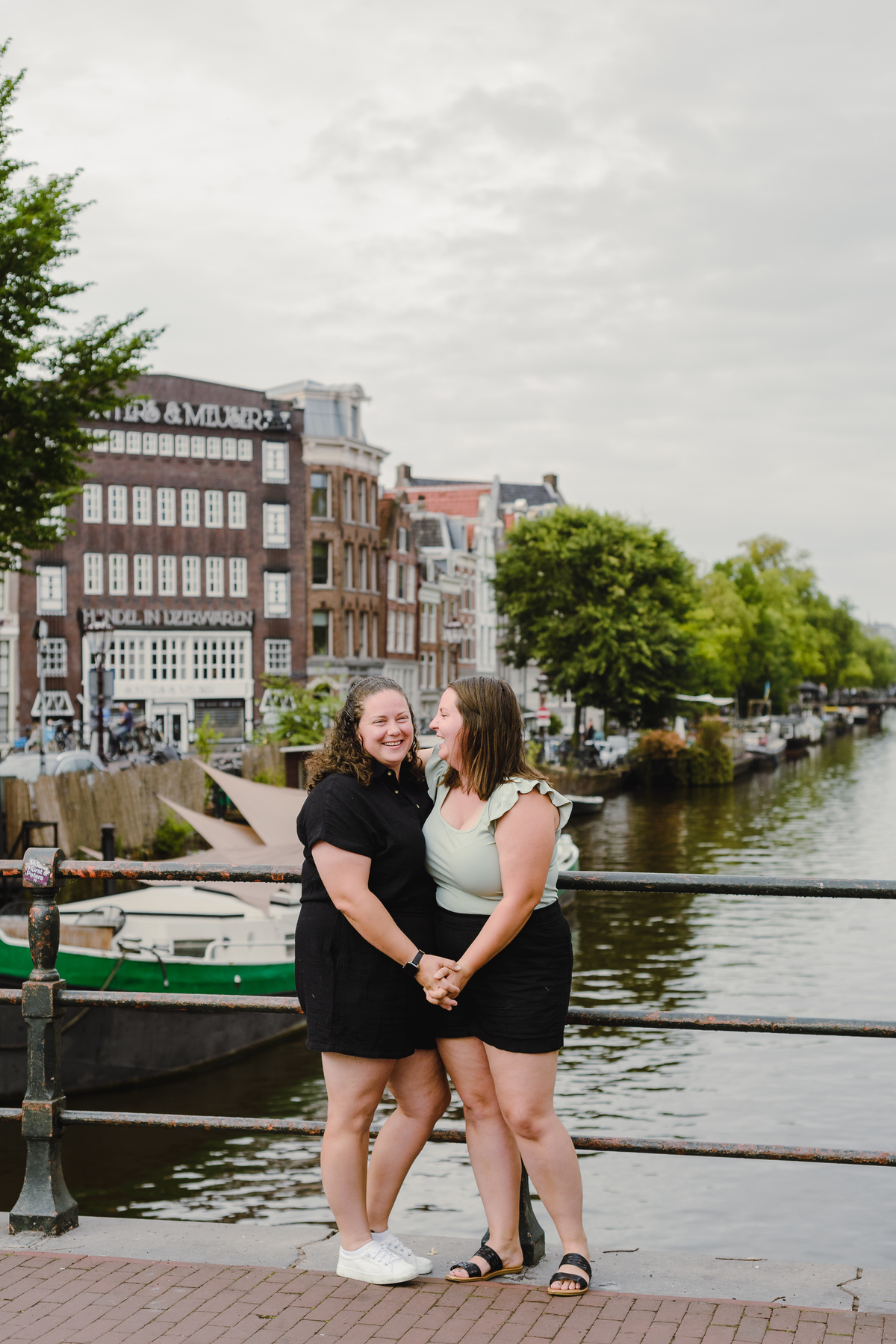 Same-sex couple photographed with historic Amsterdam architecture in the background