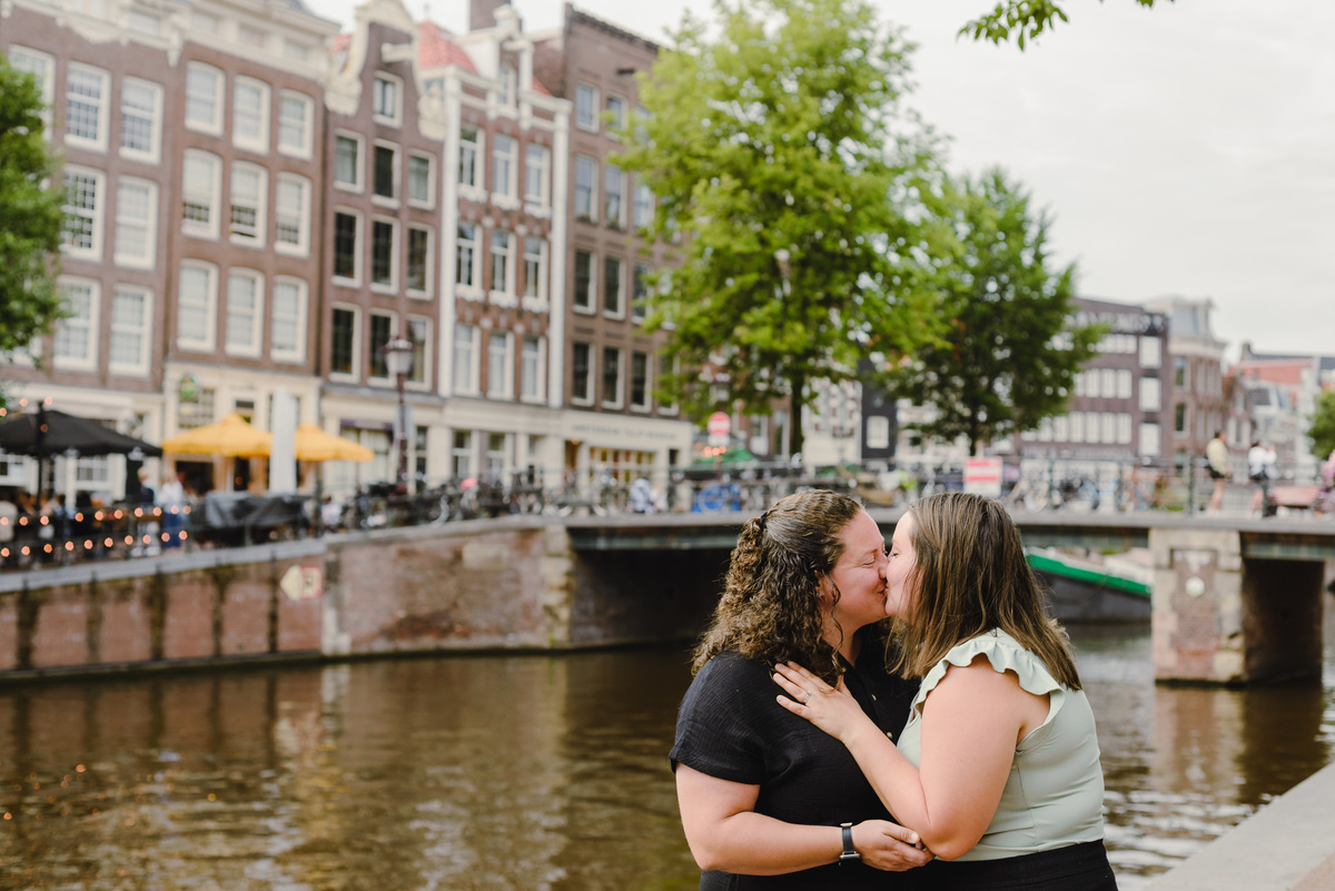 Same-sex couple photographed with historic Amsterdam architecture in the background