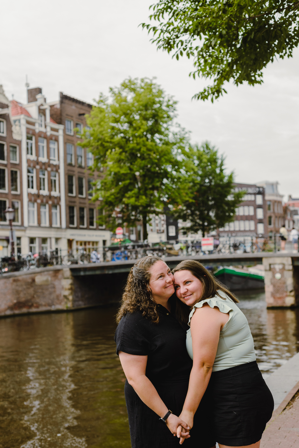 Same-sex couple photographed with historic Amsterdam architecture in the background