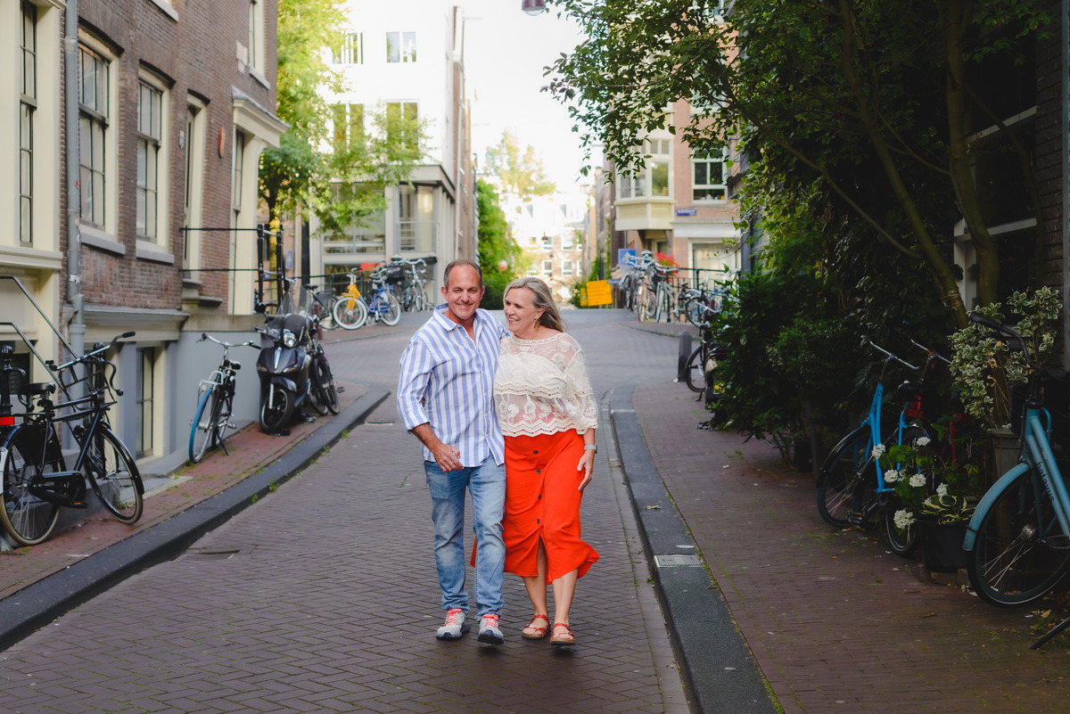 Couple walking along Amsterdam canal with historic buildings