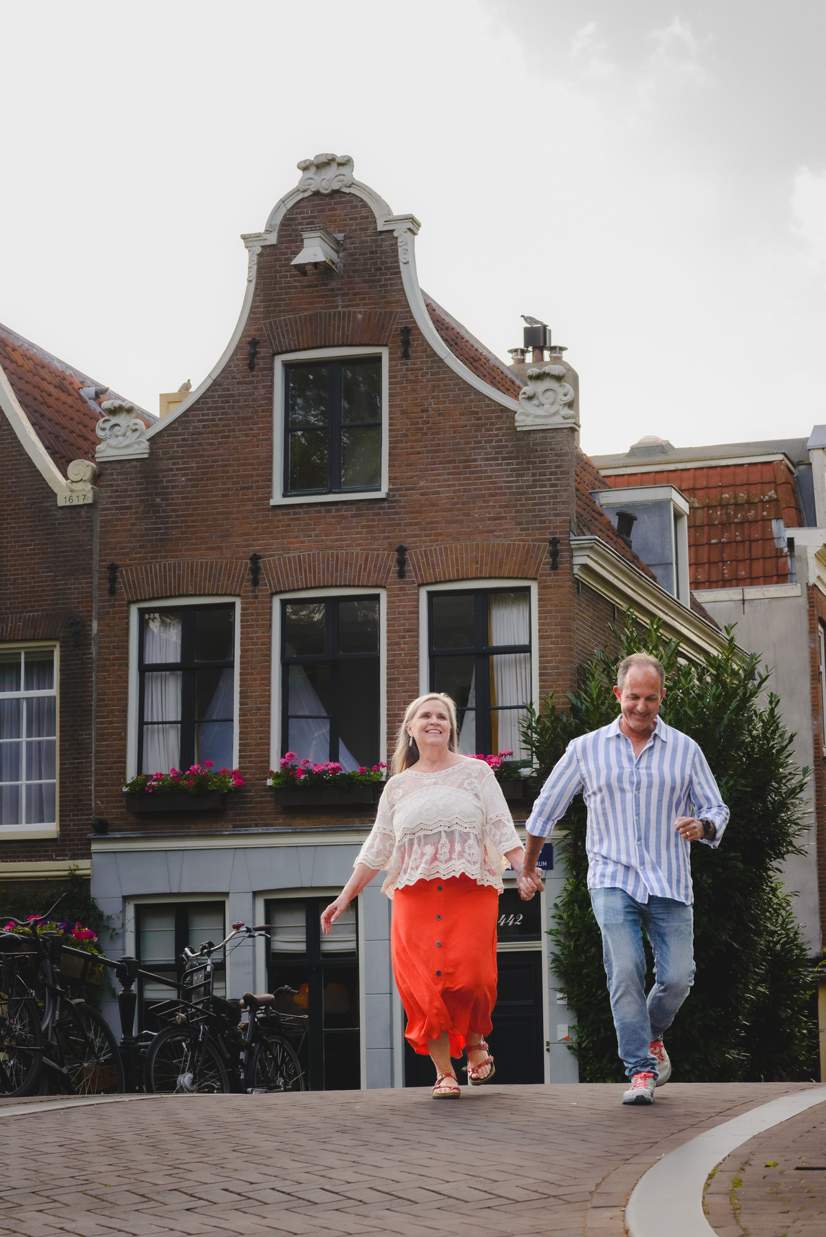 Couple walking along Amsterdam canal with historic buildings