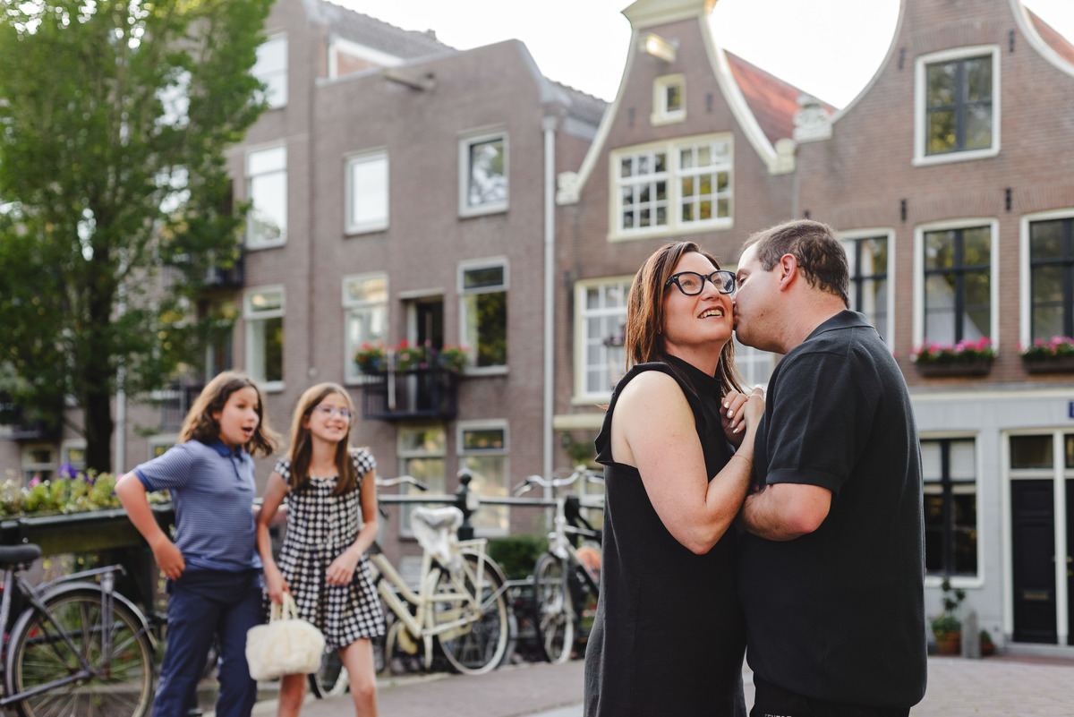 Parents together during family photo session in Amsterdam while children observe