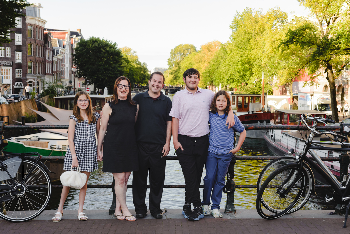 Family photo session in Amsterdam with canal behind, parents and children standing together